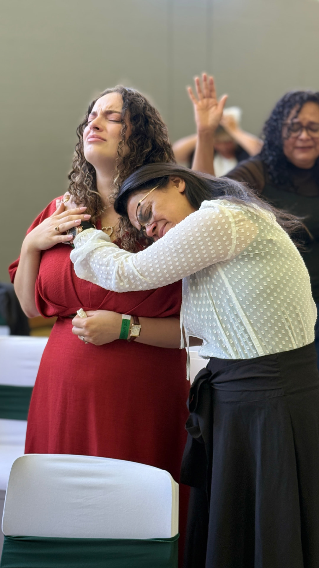 Duas mulheres abraçadas em oração durante um momento de acolhimento